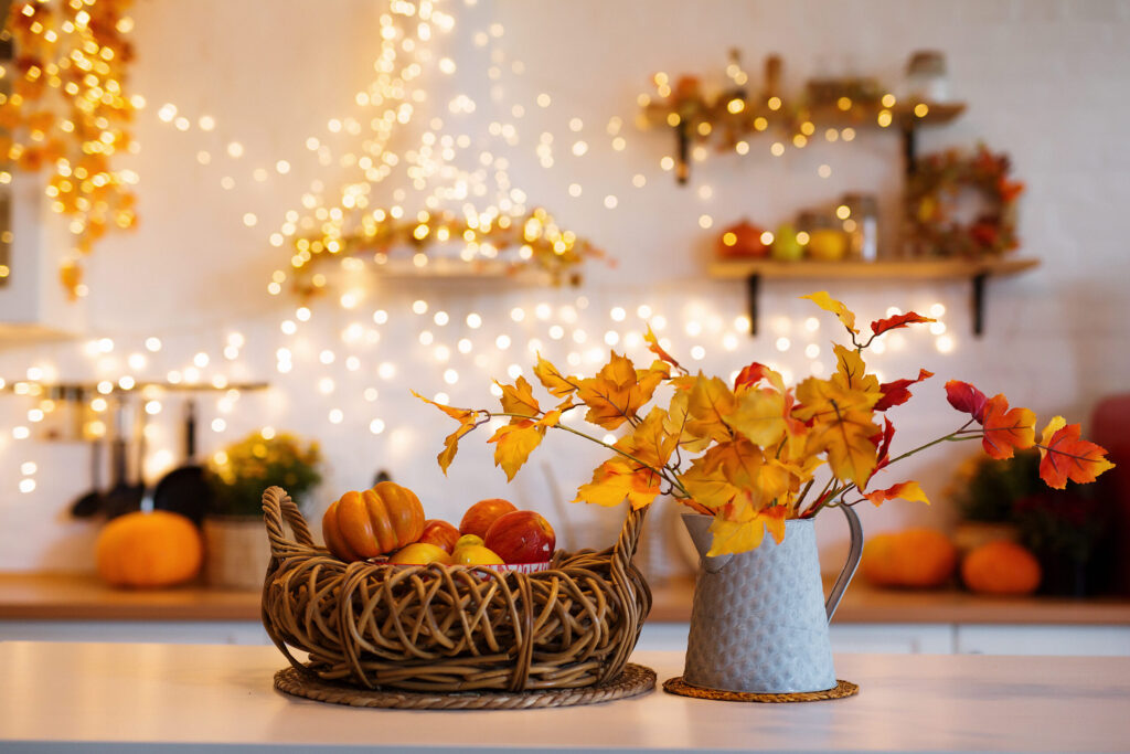 Autumn kitchen interior. Red and yellow leaves and flowers in the vase and pumpkin on light background